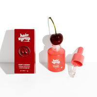 Hair Syrup Very Cherry hair growth promoting hair moisturizing treatment shown with its red packaging box, a clear bottle topped with a cherry, and an open dropper on a white background.