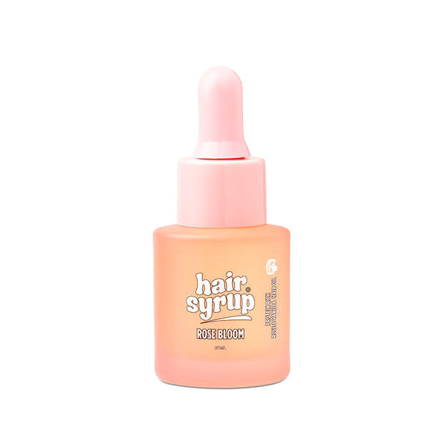A bottle of Rose Bloom Hair Syrup in the Rose Gold shade, featuring a light pink dropper cap and a peachy-pink bottle with white and black text on the front, set against a plain white background.