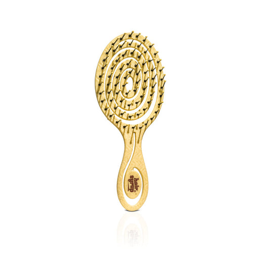 A gold-colored metal hairbrush with a spiral pattern of bristles and a decorative handle featuring an engraved symbol, shown on a white background with a soft reflection.