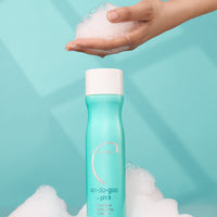 Hand holding a foamy product above a bottle labeled 'un-da-goo' with a light blue background.