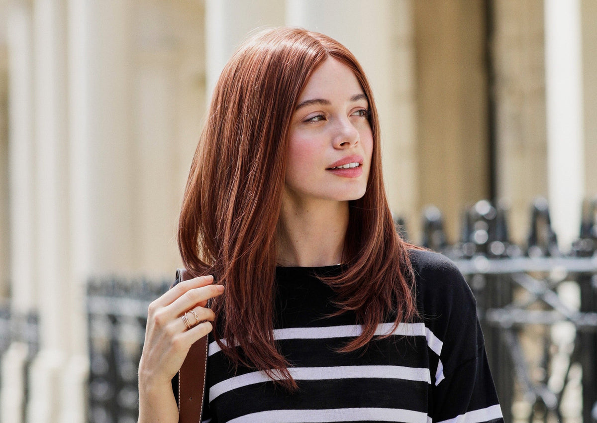 Woman with red hair wearing a black and white striped sweater outdoors.