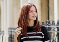 Woman with red hair wearing a black and white striped sweater outdoors.